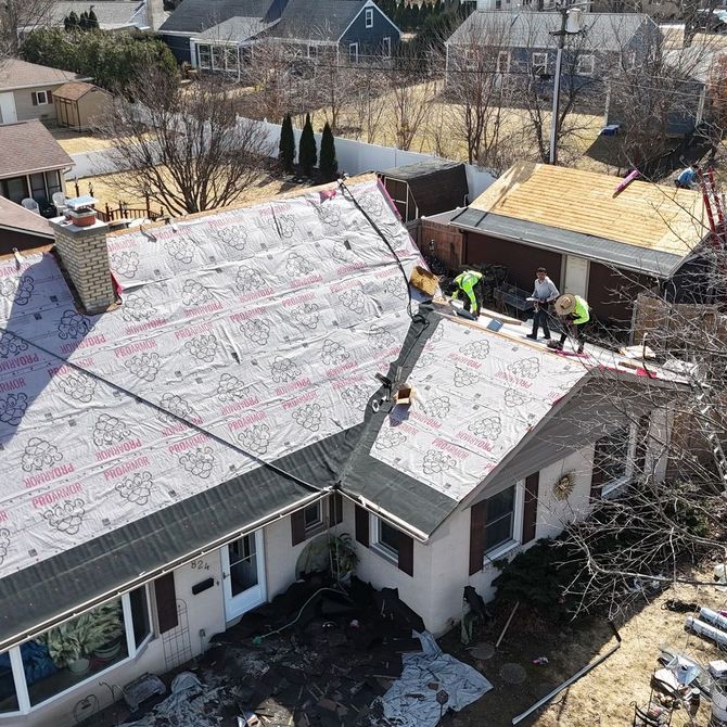 A group of people are working on the roof of a house.