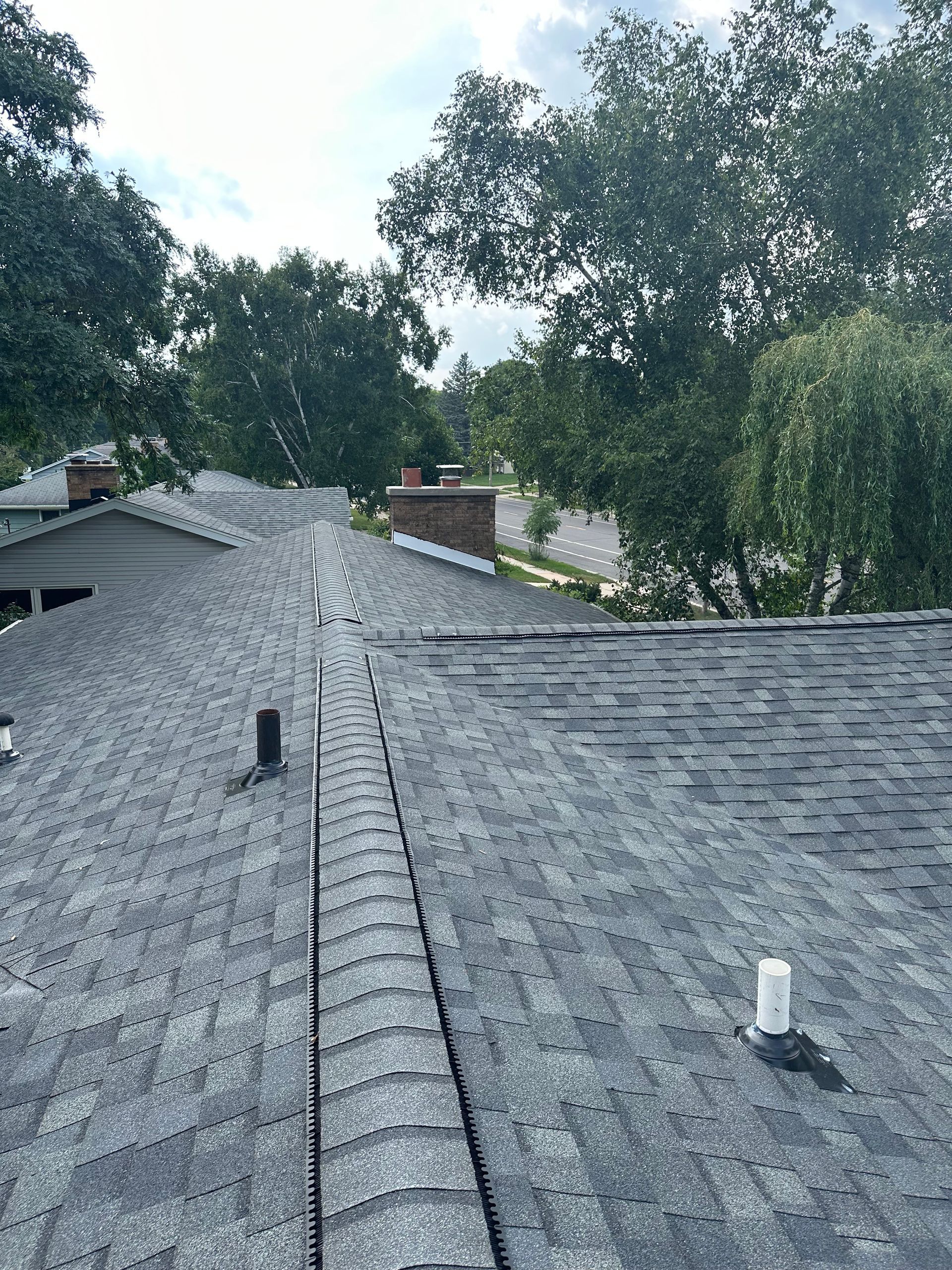 A roof with a lot of shingles and trees in the background.