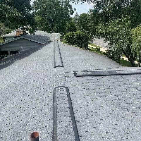 A roof with a chimney on it and trees in the background.