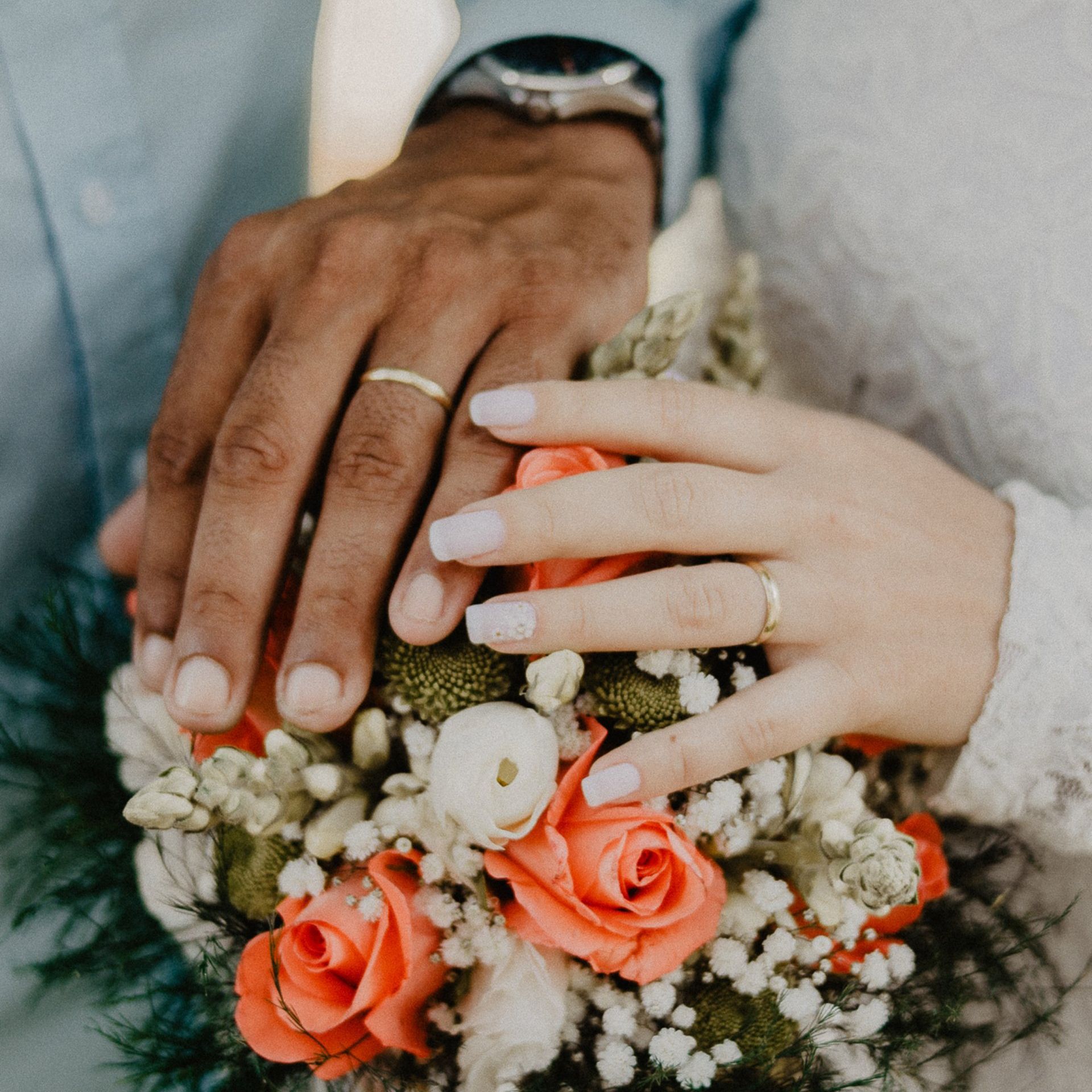 Een bruid en bruidegom die elkaars handen vasthouden met een boeket bloemen