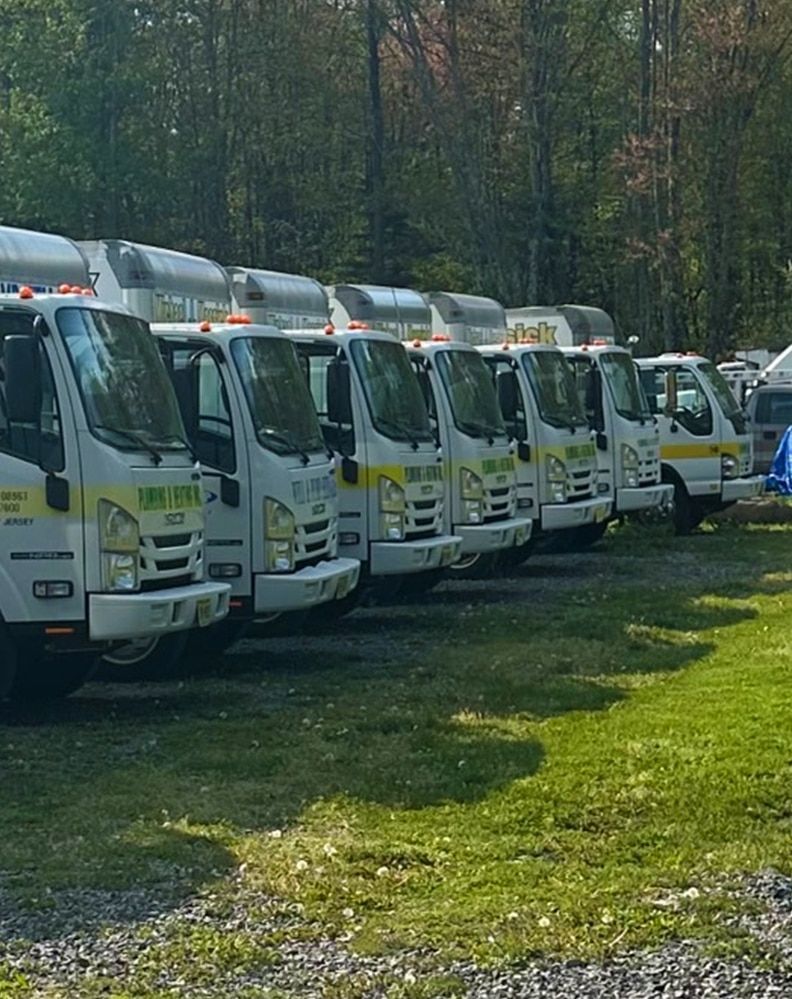 A row of trucks are parked in a grassy area.
