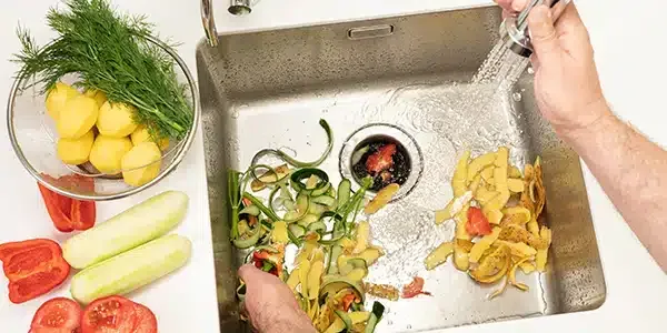 A person is washing vegetables in a sink.