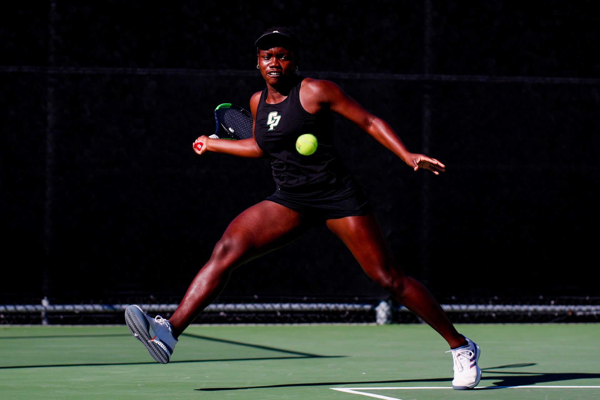 Tennis player lunging to return a ball on a dimly lit court