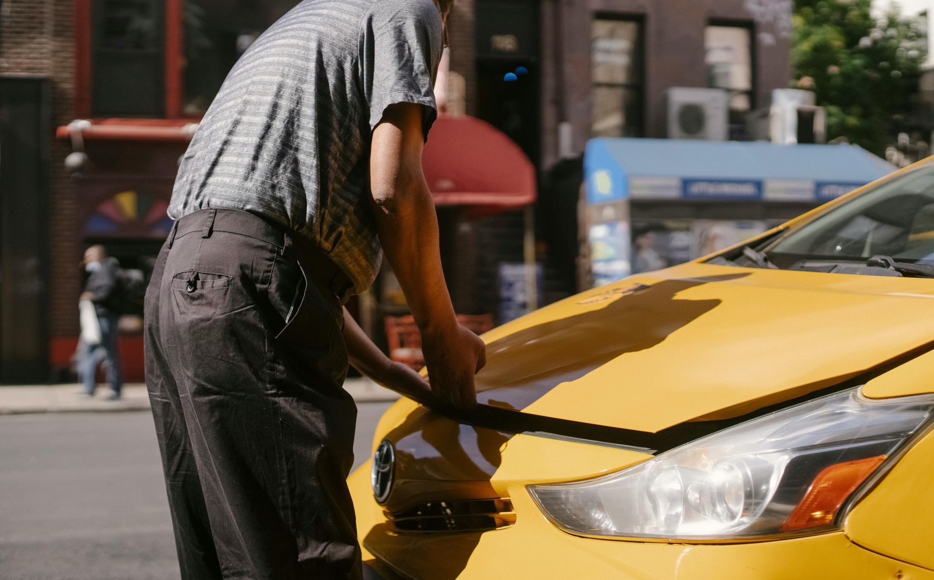 A man is working on a broken down car on the side of the road.