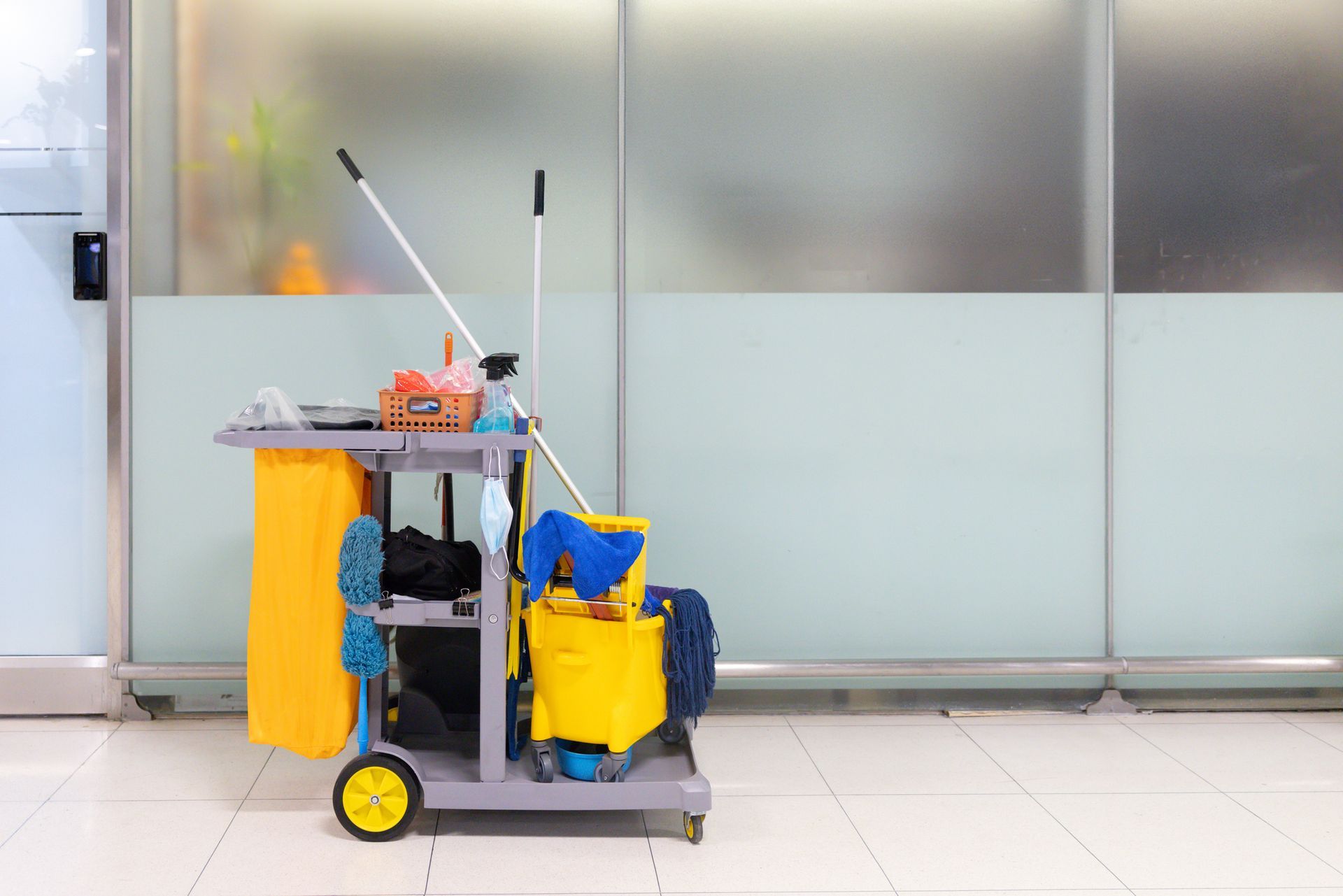 A cleaning cart with a yellow bucket and a blue mop.