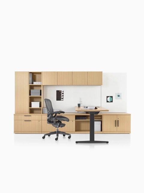 Modern home office with wood storage cabinets, black chair, desk, and shelving on a white wall