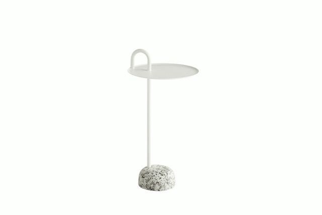 Minimal white side table with a thin stem and a textured stone base on a white background