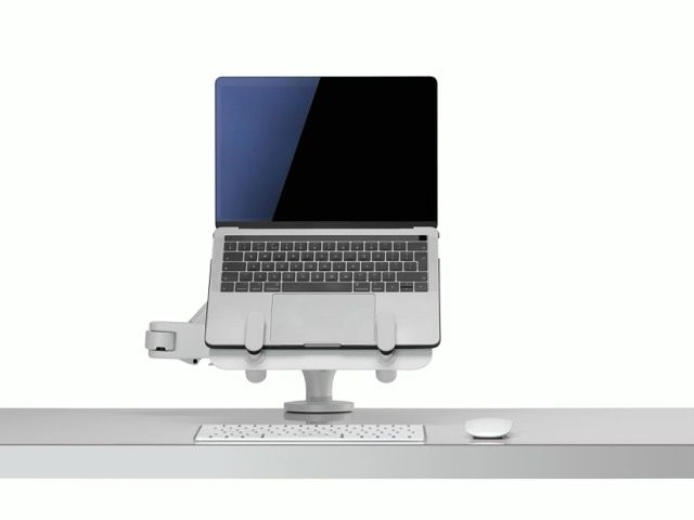 Laptop with a blue-and-black screen on a desk, connected to a white keyboard and mouse under a monitor stand