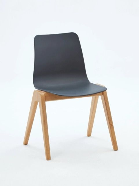 Modern chair with a dark gray molded seat and light wood legs on a white background