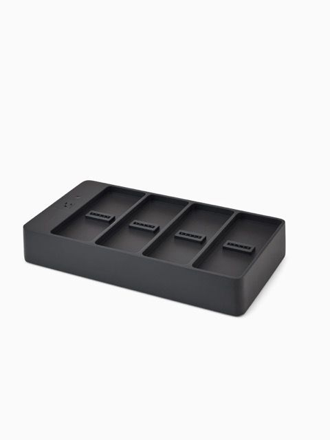 Black four-slot charging dock on a rectangular base with USB ports on each unit