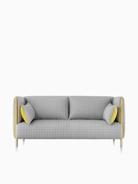 Gray upholstered sofa with yellow accent pillows on a white background