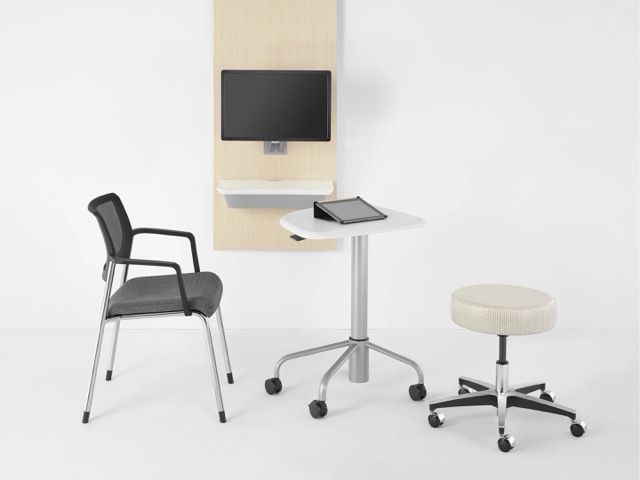 Wall-mounted monitor with adjustable arm beside a mobile standing lectern on wheels