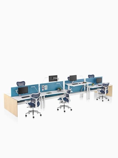 Modern office workspace with three blue computer desks, monitors, and swivel chairs