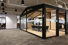 Glass meeting pod with black frame in an open office space