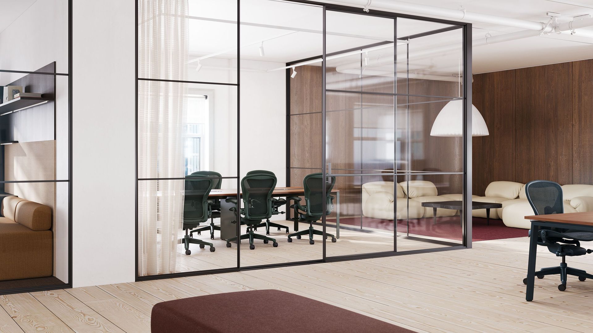 Modern office with glass meeting room, green chairs, wood paneling, and a hanging white lamp.