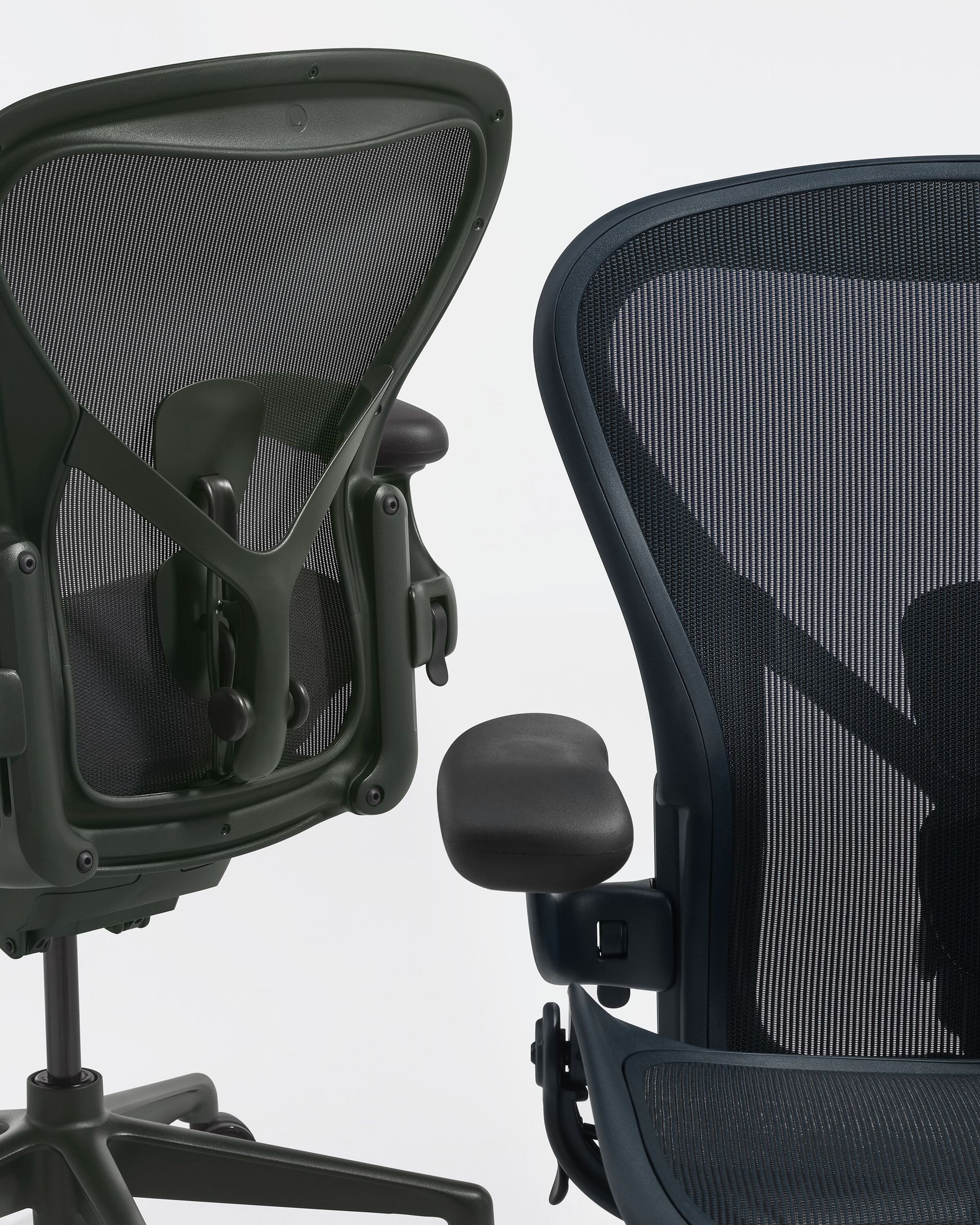 Two black mesh office chairs viewed from behind and side, with armrests and adjustable backs