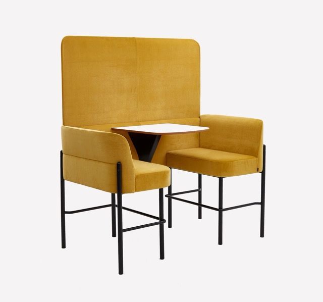 Mustard-yellow upholstered chair with attached side tables and black metal legs on a white background