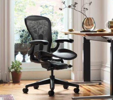 Black ergonomic office chair beside a desk in a sunlit home office