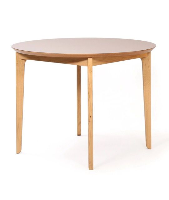 Round wooden table with light wood legs and a beige top on a white background