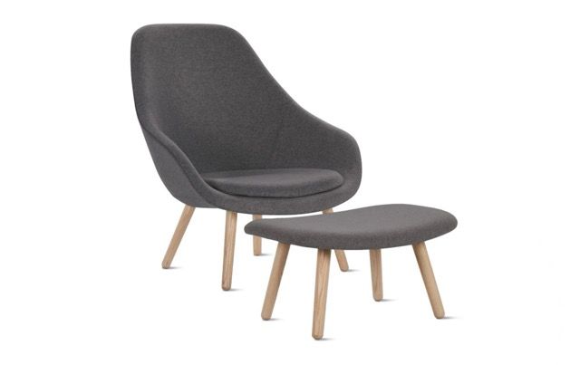 Dark gray upholstered lounge chair with matching ottoman and light wood legs on a white background