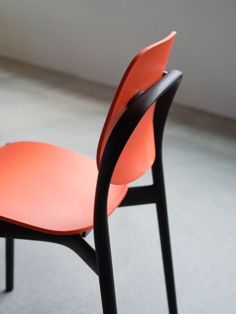 Orange and black modern chair against a gray wall