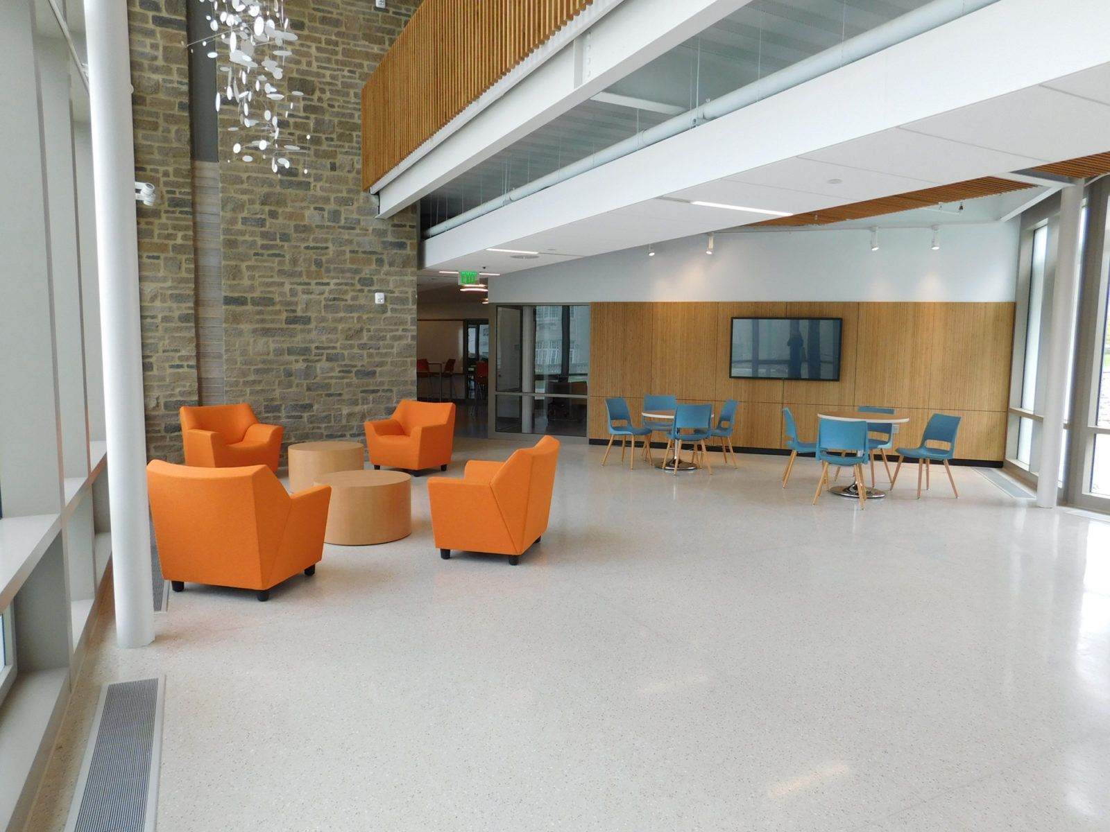 Modern lounge with orange chairs, blue tables, and a brick-and-wood interior