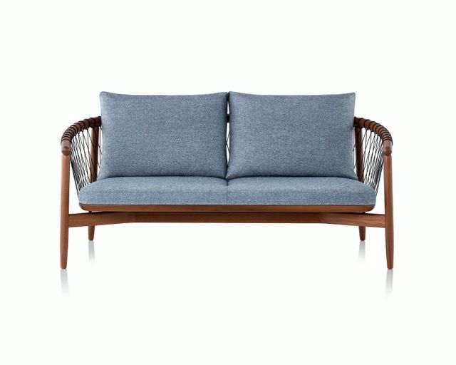 Blue cushioned wooden loveseat with woven armrests on a white background