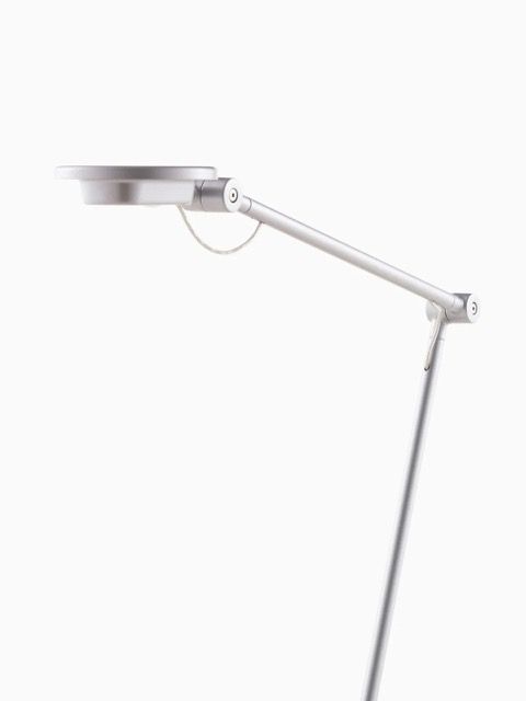 White adjustable desk lamp with a long arm on a plain light background