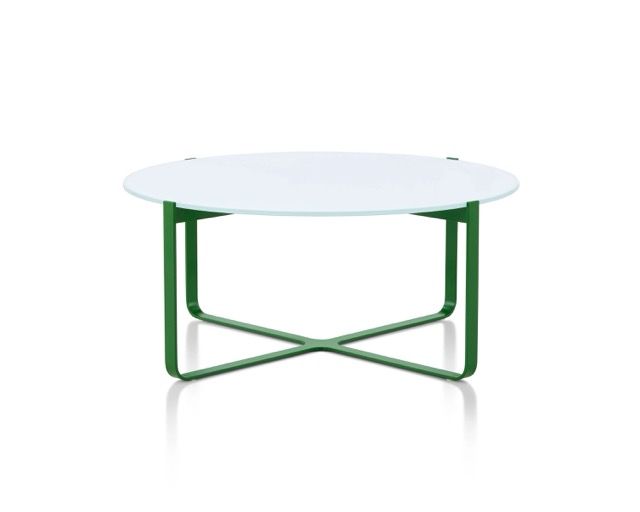 Round glass-top table with green metal legs on a white background