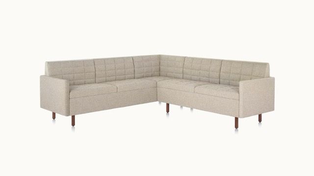 Beige L-shaped sectional sofa with dark wooden legs on a white background