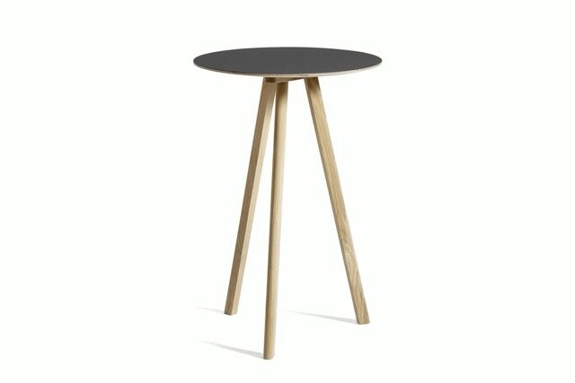 Small round black tabletop with four light wooden legs on a white background