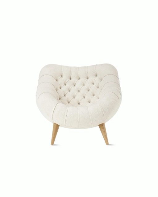 Cream tufted lounge chair with wooden legs on a white background