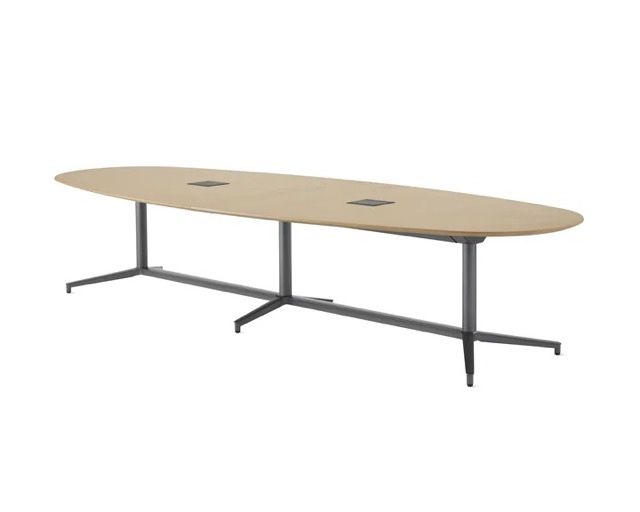 Oval beige conference table with dark metal legs and two cable grommets