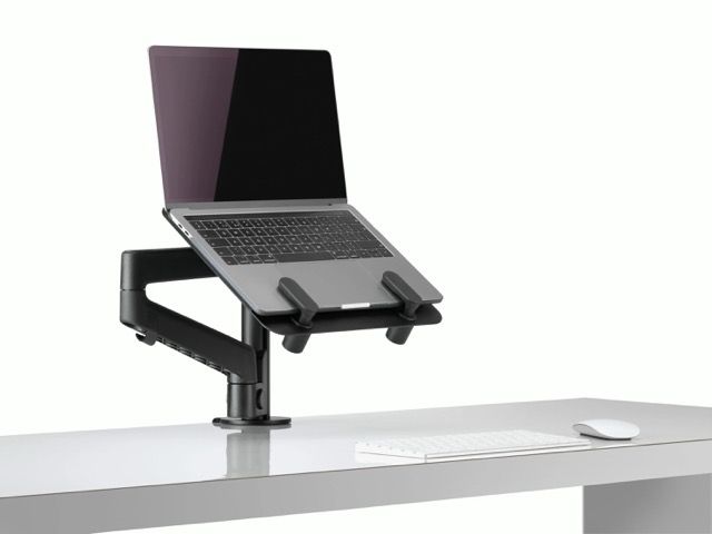 Laptop on adjustable desk mount above a white table with a mouse
