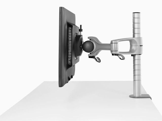Flat-panel monitor mounted on an adjustable arm attached to a vertical pole beside a desk surface