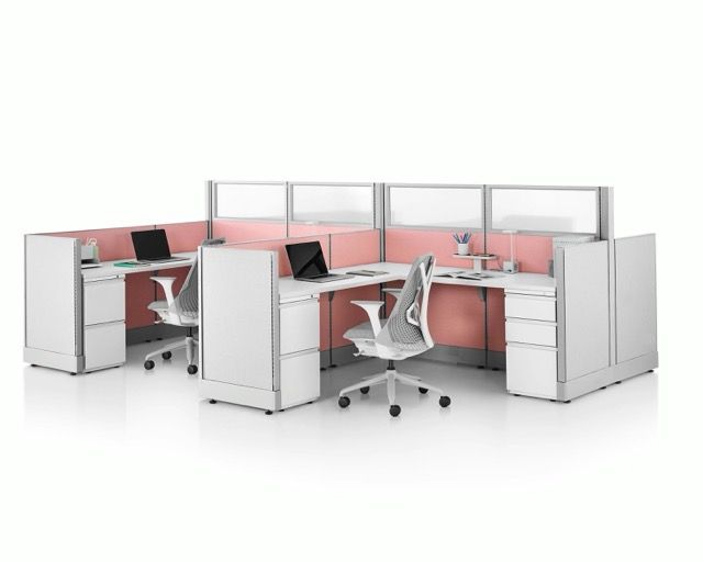 Modern office cubicles with pink partitions and white desks, featuring swivel chairs in an open workspace