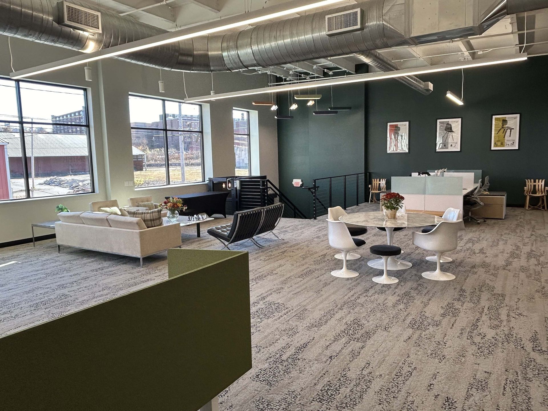 Modern office lounge with white chairs, sofas, tables, and large windows in an open workspace