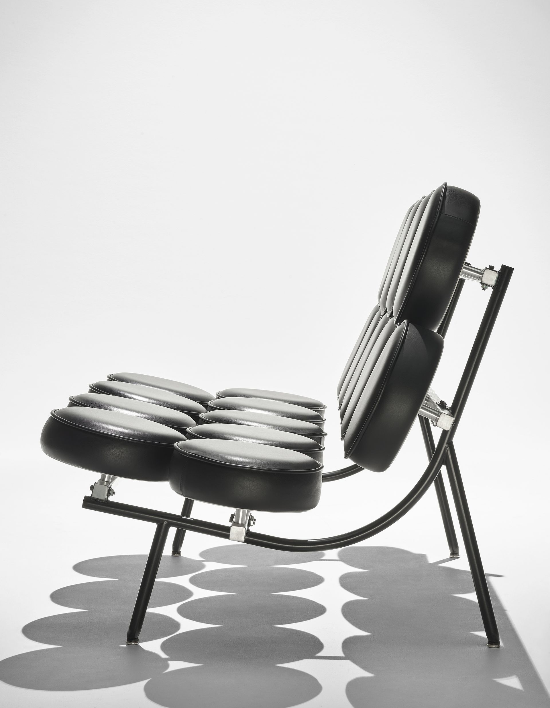 Black cushioned chaise lounge chair with a tufted seat and back, shown in side view on a white background