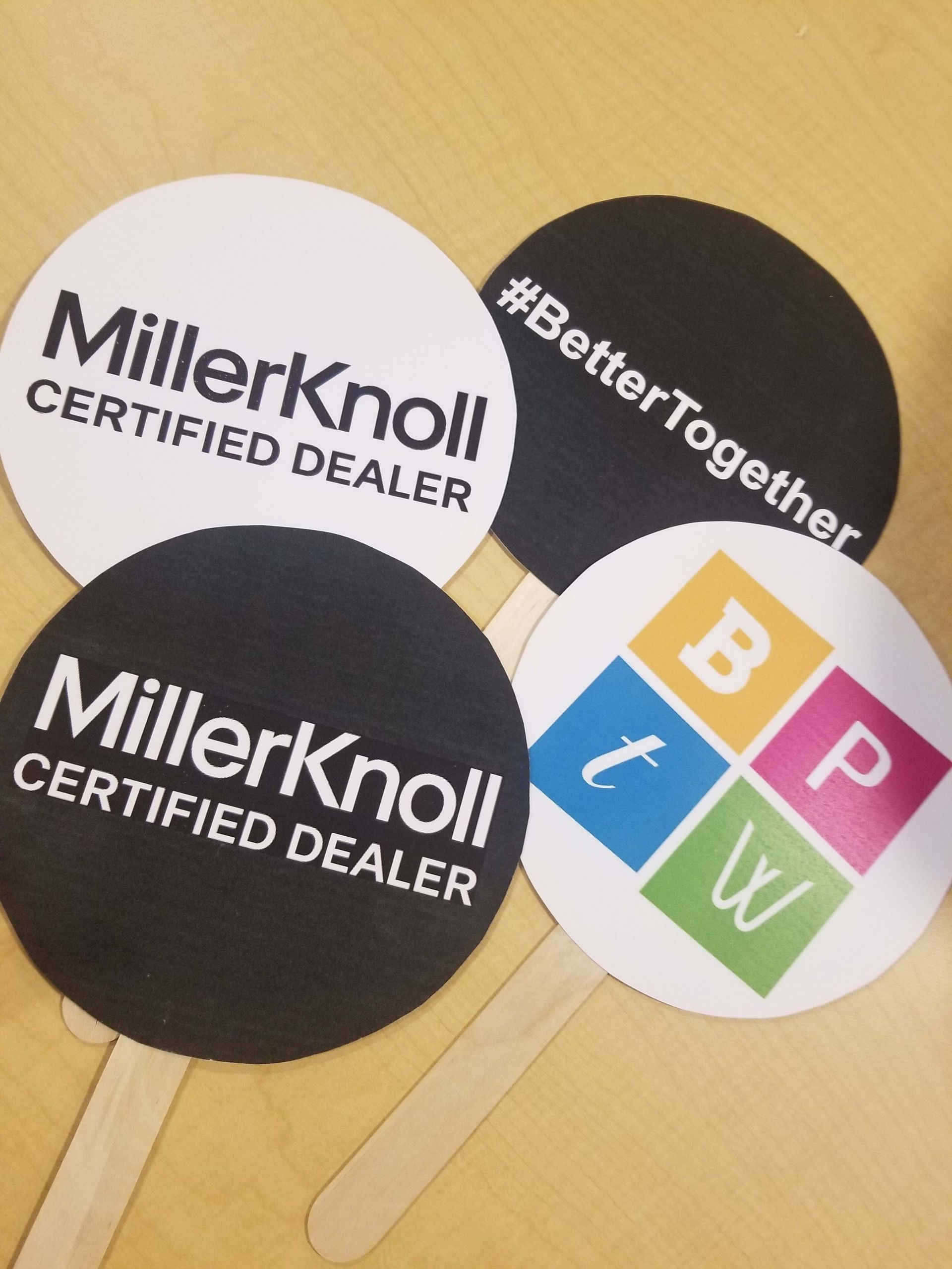 Four round dealer stickers, including MillerKnoll Certified Dealer and Better Together logos, on a tan surface