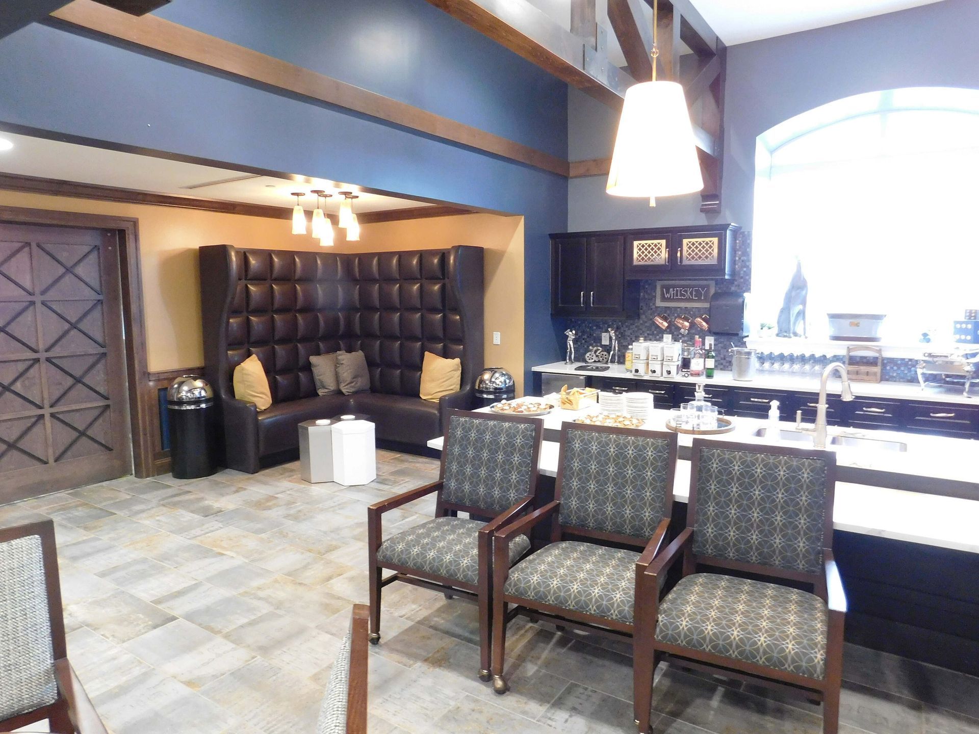 Modern hotel lobby with tufted seating, tiled floor, and a bright windowed seating area