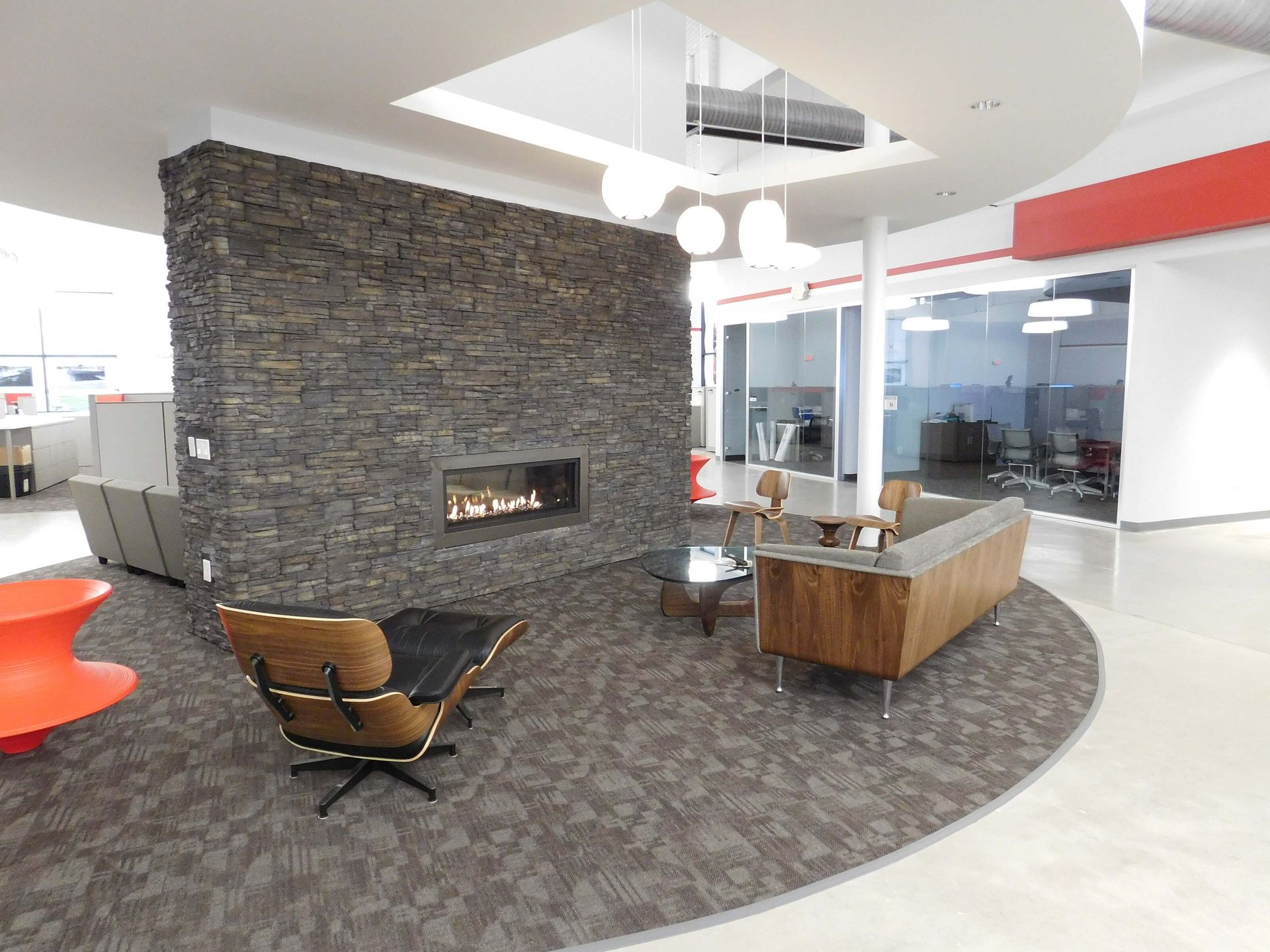Modern office lounge with stone fireplace, curved carpet, and wood seating area