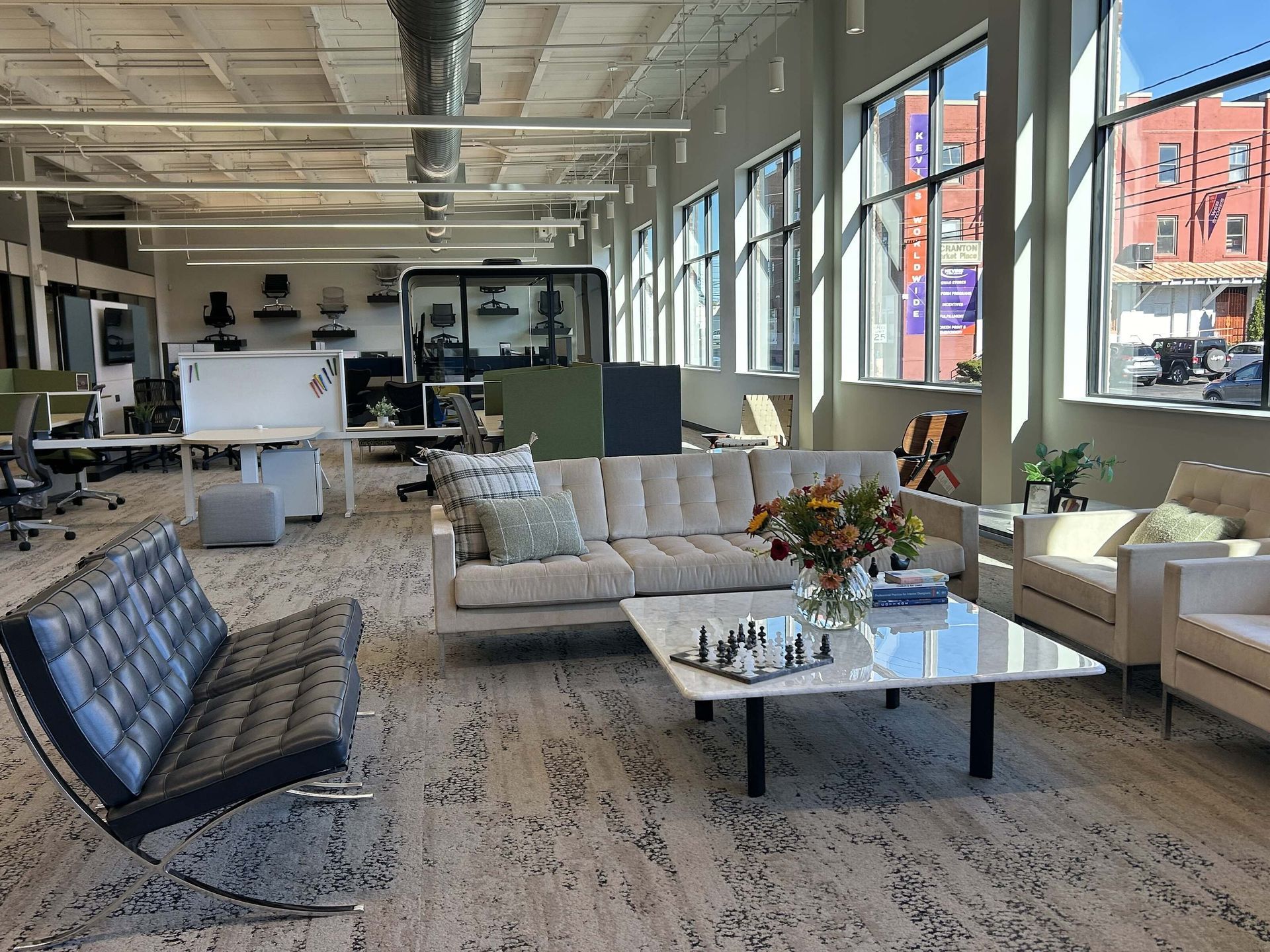 Modern office lounge with sofas, chairs, coffee table, and large windows