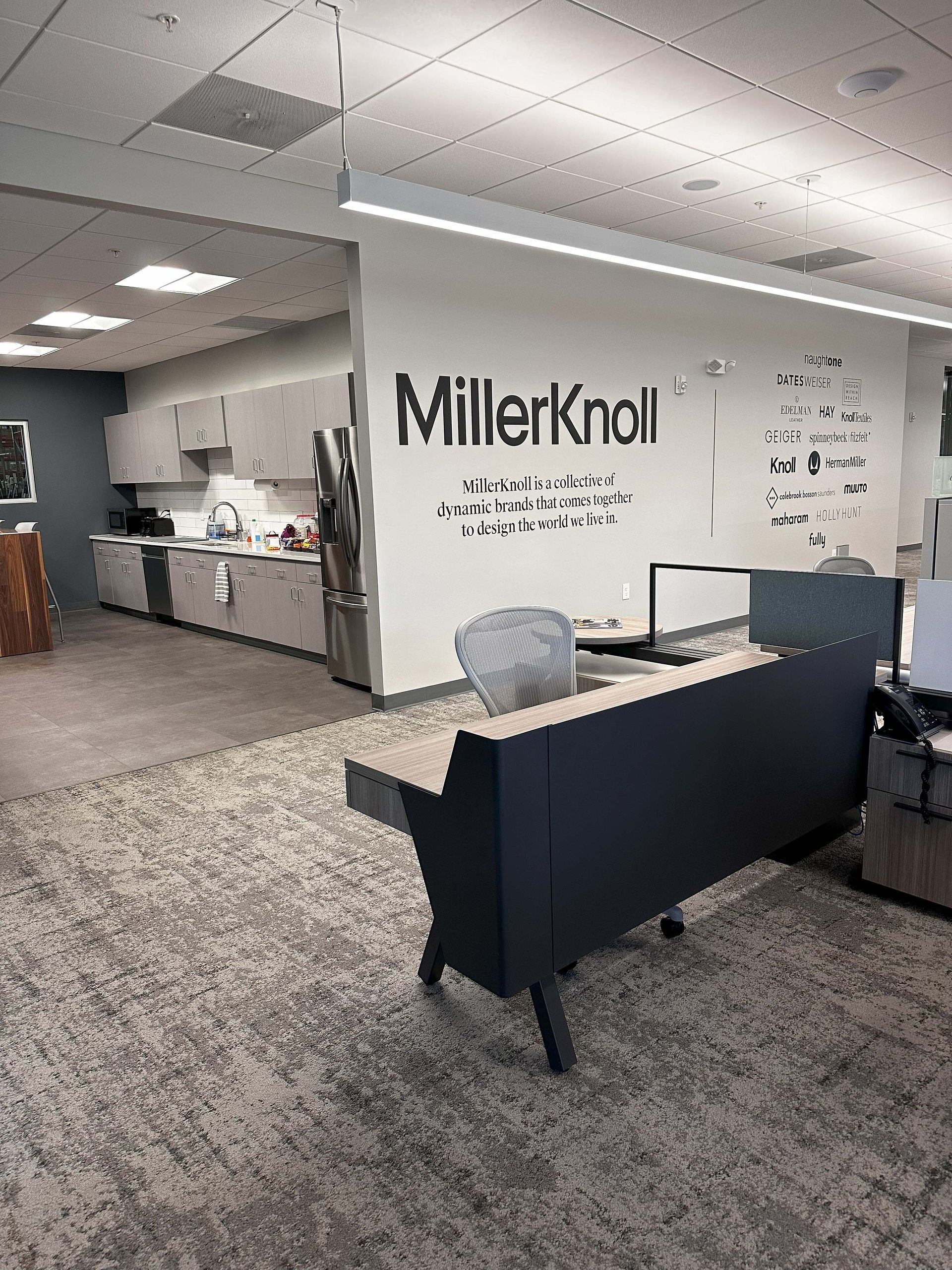 MillerKnoll office lobby with reception desk, gray chairs, and wall logo.