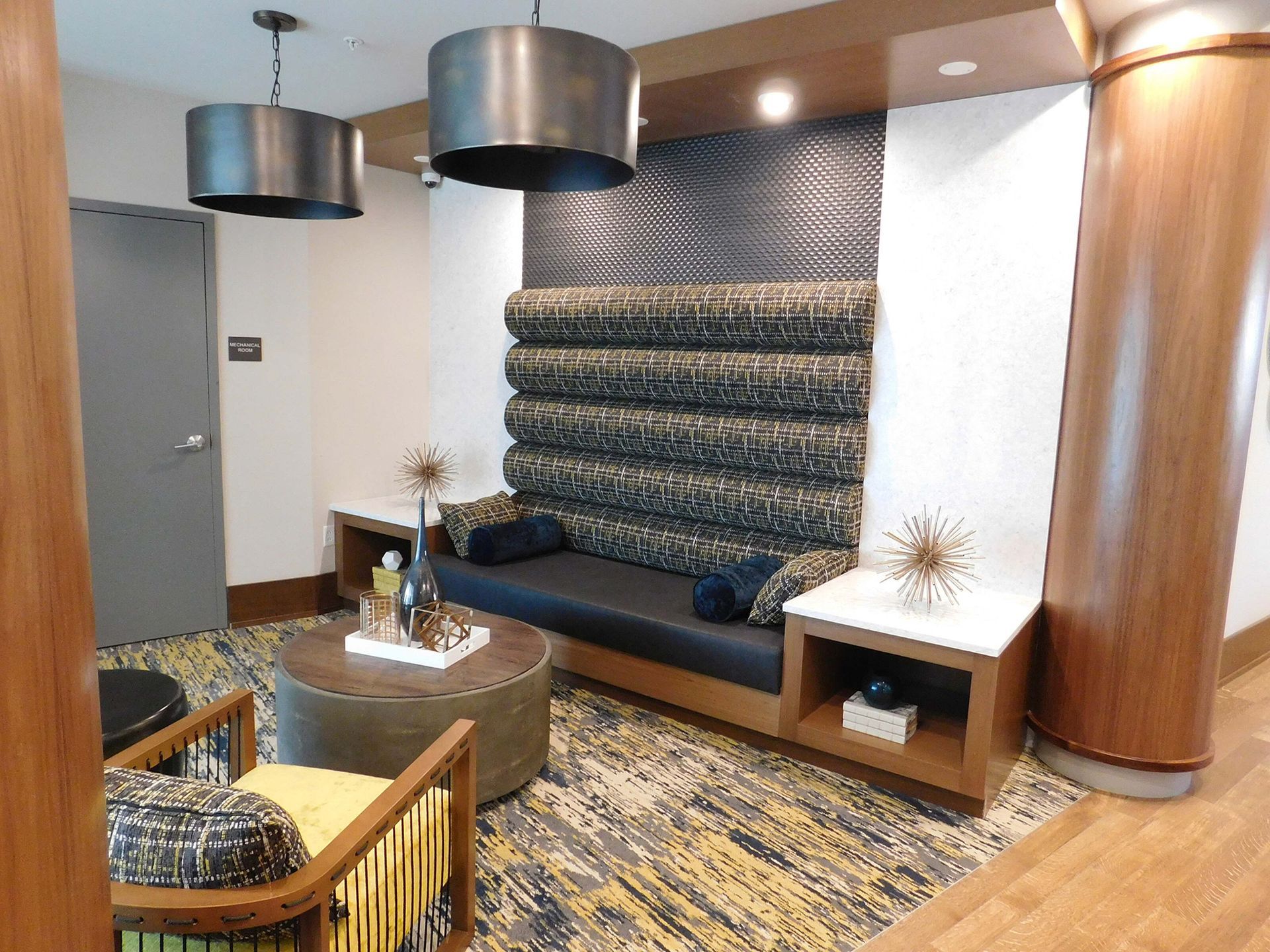 Modern lounge with patterned blue sofa, round chairs, wooden tables, and abstract wall art