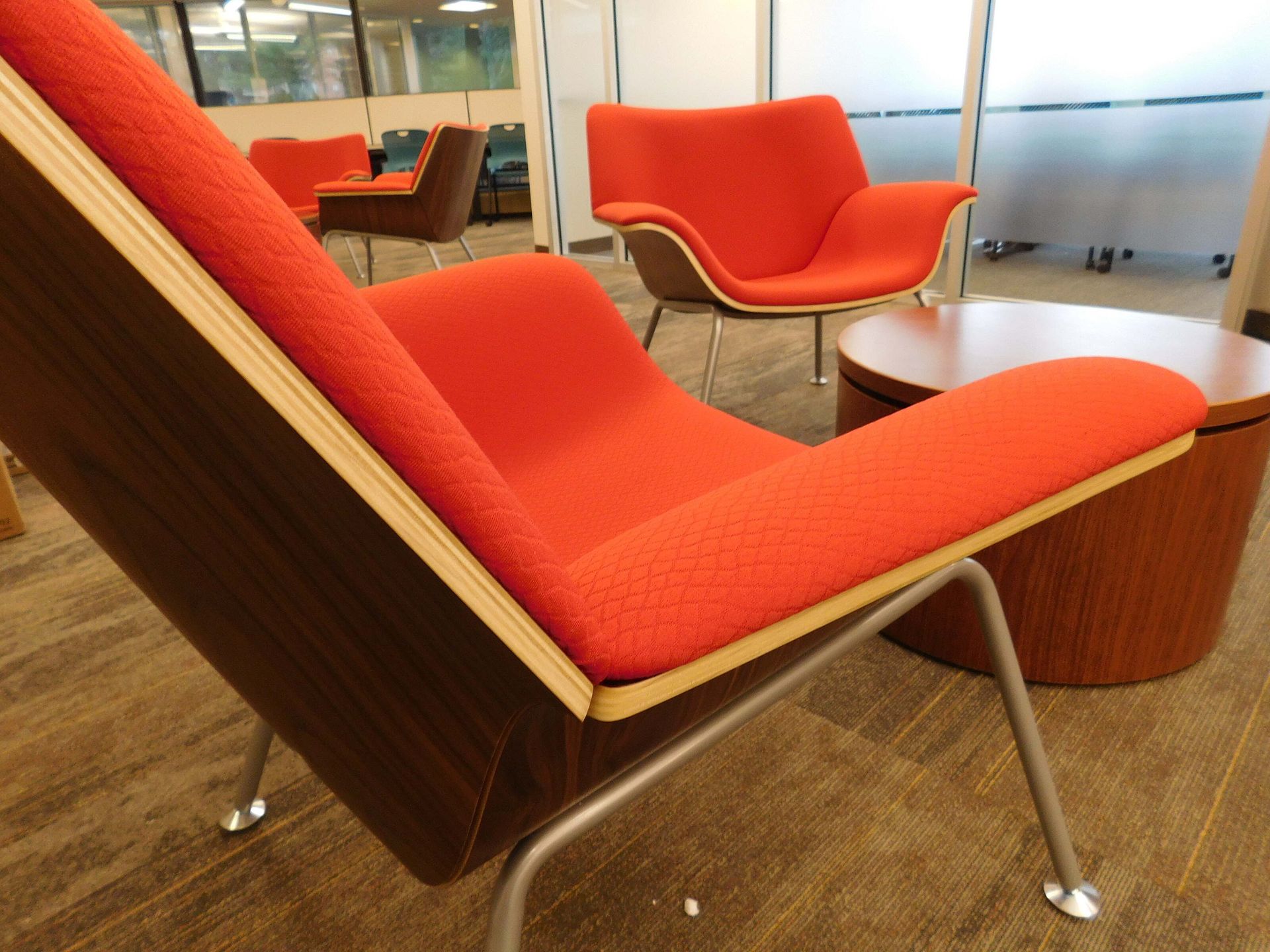 Modern lounge chairs with red-orange upholstery in a bright office lounge