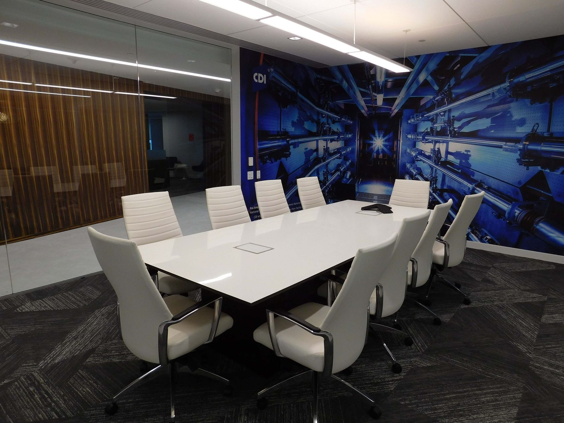 Modern conference room with a long white table, black chairs, and blue abstract wall art