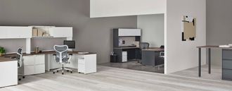 Modern open-plan kitchen and living area with white cabinets, gray walls, and a dining table in the foreground