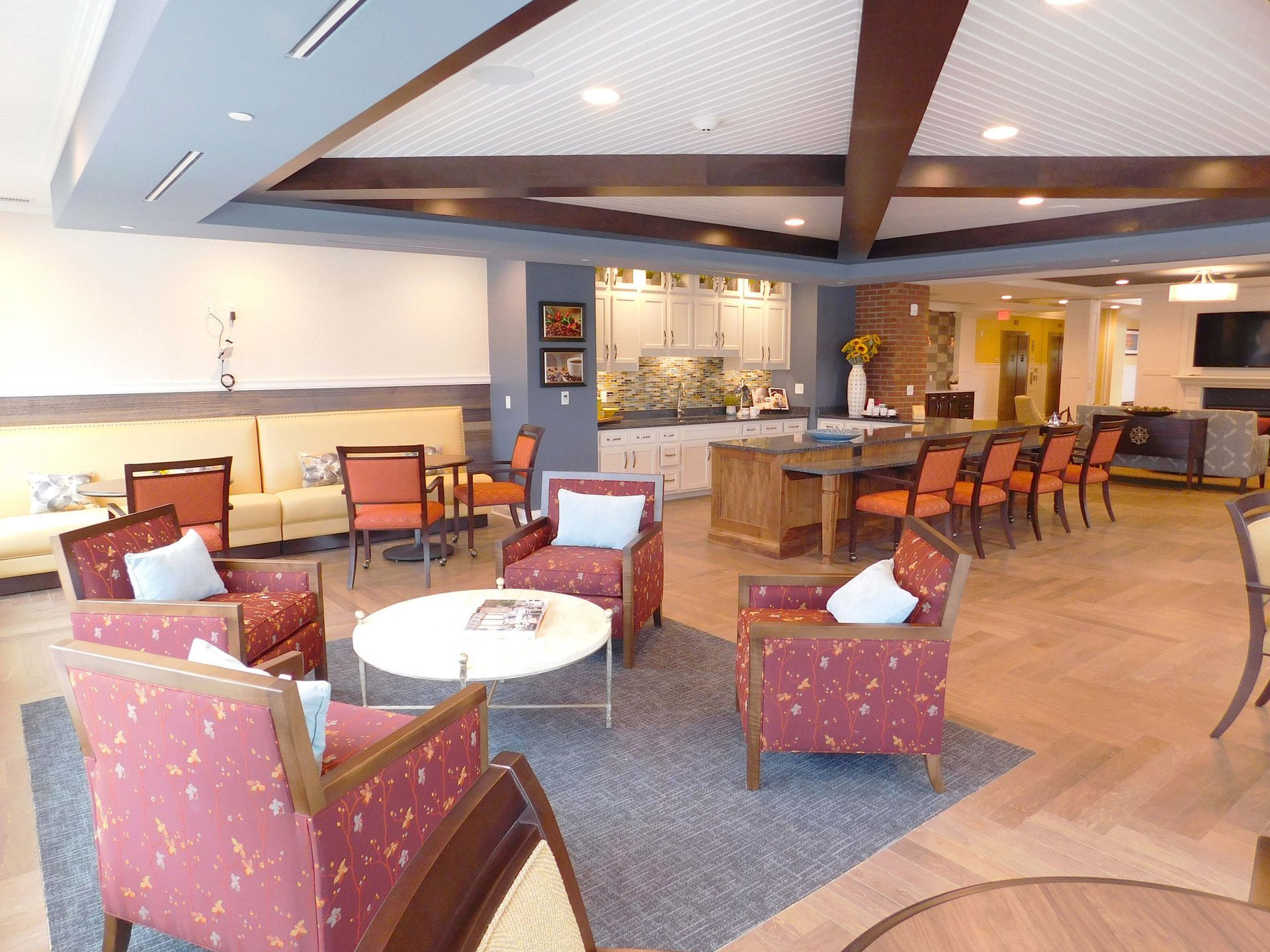 Spacious hotel lobby with lounge chairs, round tables, and a central bar area under warm lighting