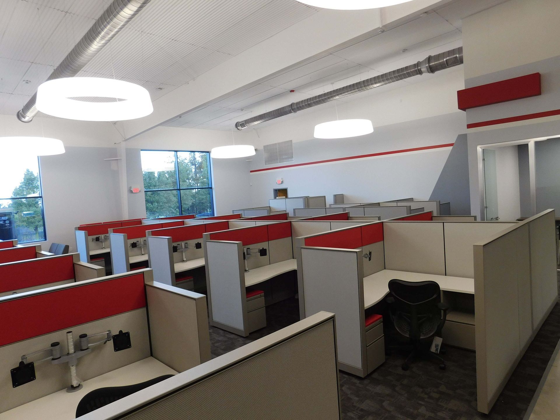 Empty office with red and beige cubicles under bright ceiling lights