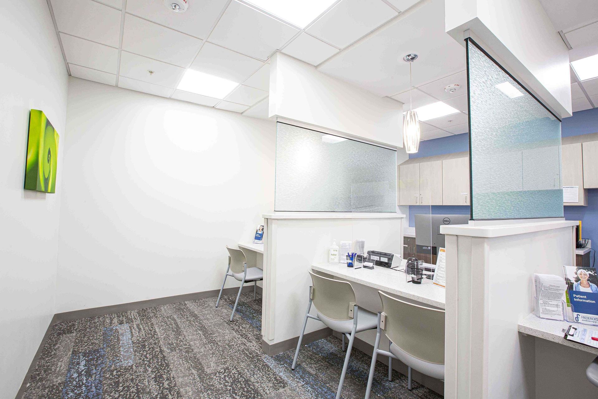 Modern office cubicles with white walls, gray carpet, and bright overhead lighting